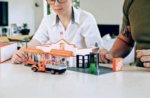 A young boy and his dad are playing with the NovaBrix Home Depot Canada store front set