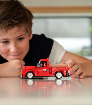 A young boy playing with a NovaBrix Ace Hardware Vintage Truck